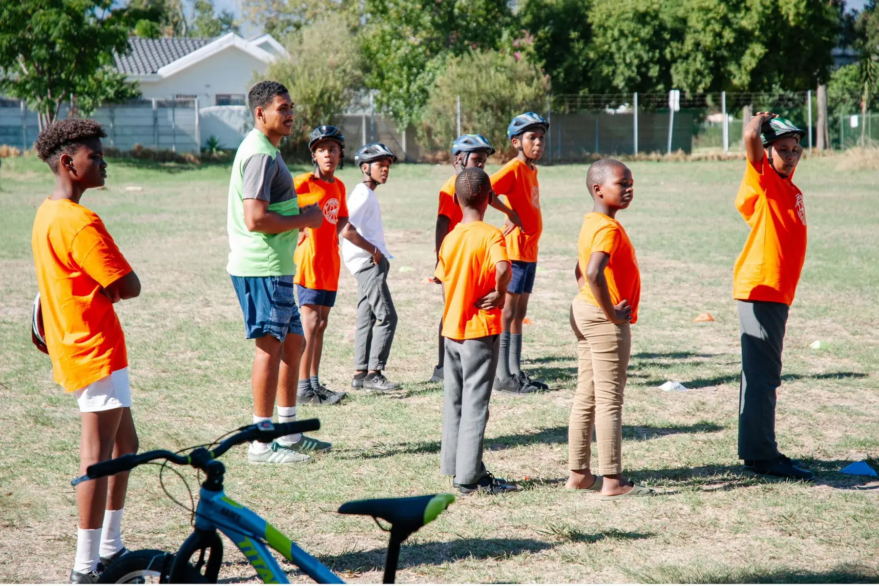Young people standing on a field behind a bicycle during a session